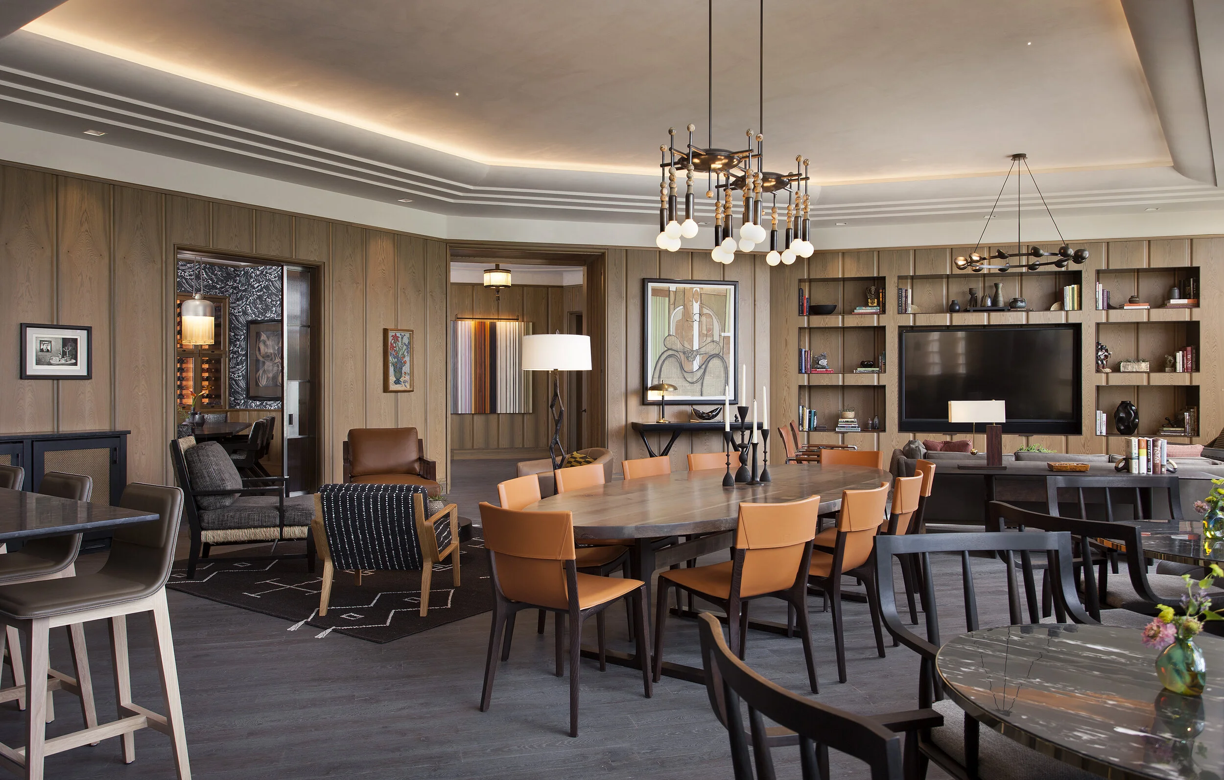 Grand open-plan dining area with a round table, cognac-upholstered chairs, and a modern brass chandelier